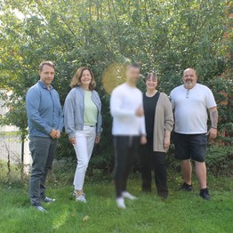 LWL-Mitarbeitende und ein Patient stehen auf einer Wiese