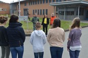 Ein Mann und zwei Frauen stehen vor einer Gruppe Schüler und erklären ihnen etwas. Im Hintergrund ist die verklinkerte Fassade der LWL-Klinik zu sehen.