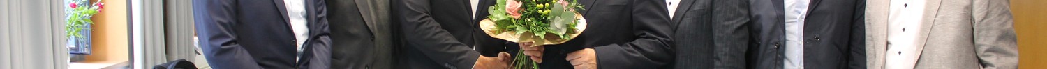 Sechs Männer in einem Konferenzraum lächeln in die Kamera.